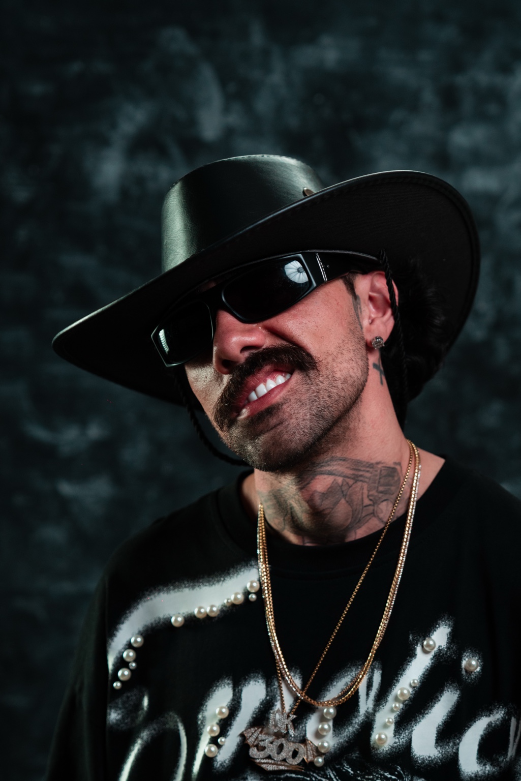 Young Flakoo con sombrero negro, gafas y su cadena 300